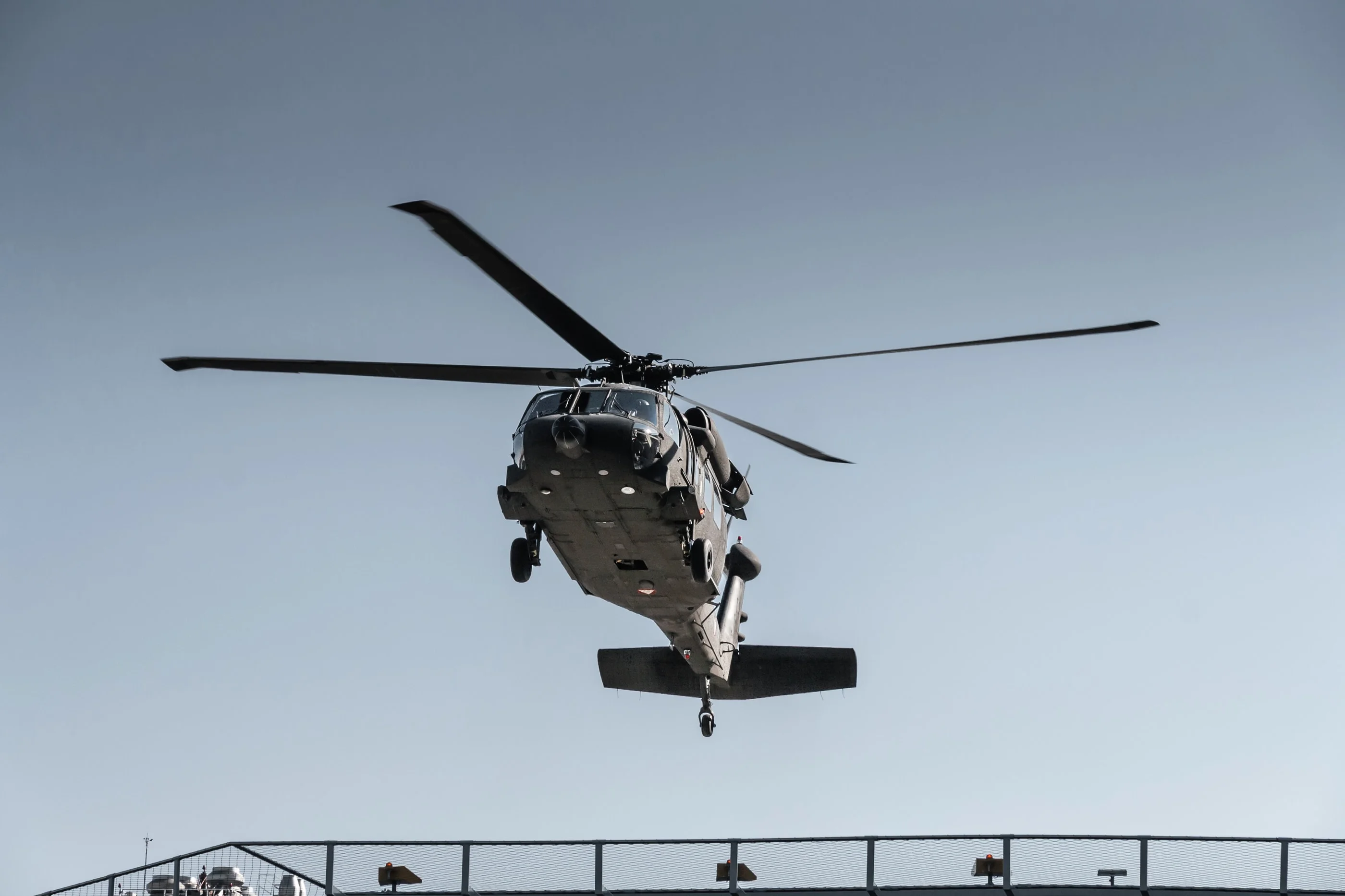 The Black Hawk approaching the rooftop helipad, seen head-on above the railing