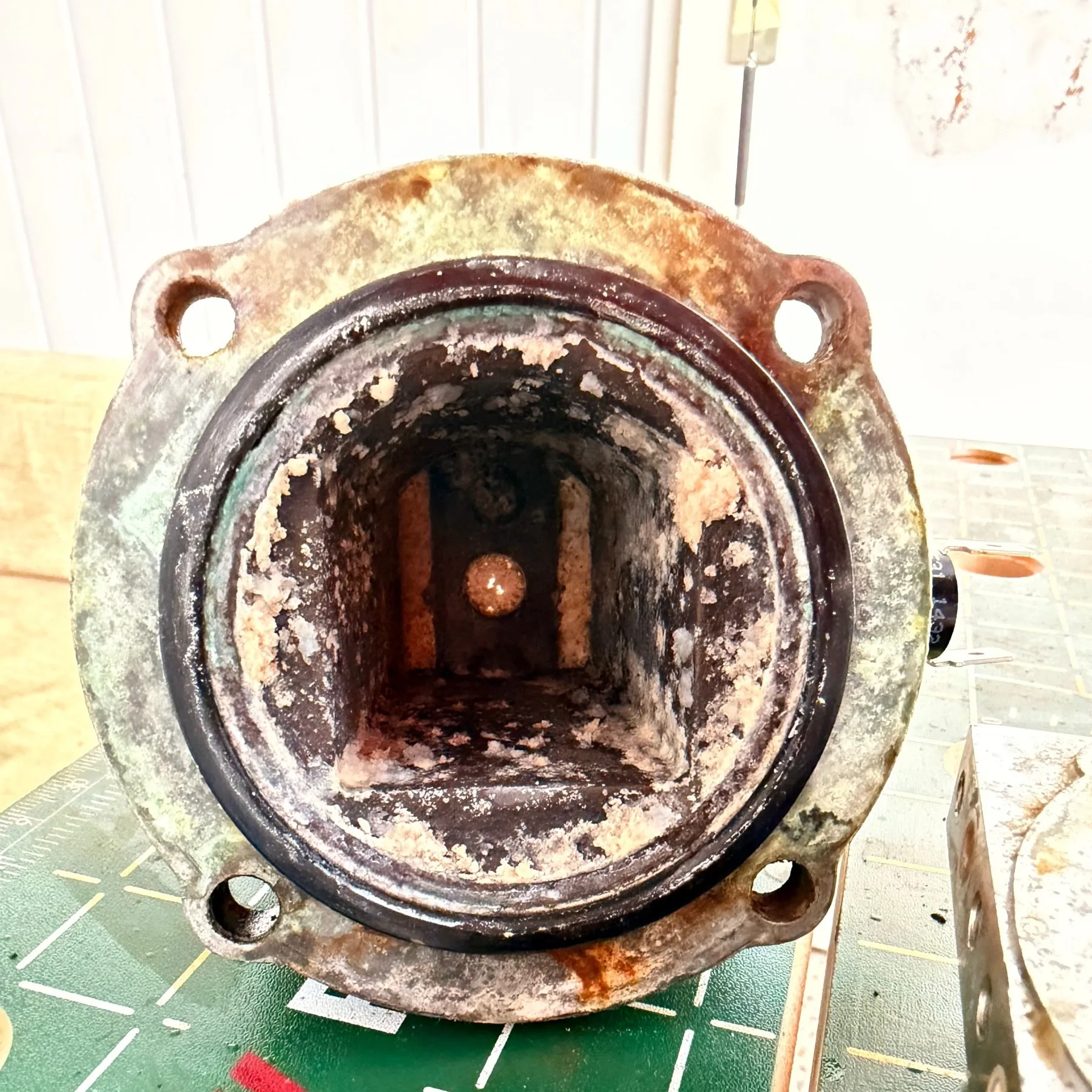 Looking into the boiler cavity through its round flange on 18 July: the square chamber is caked with white scale and black deposits, the flange face itself crusted and discoloured