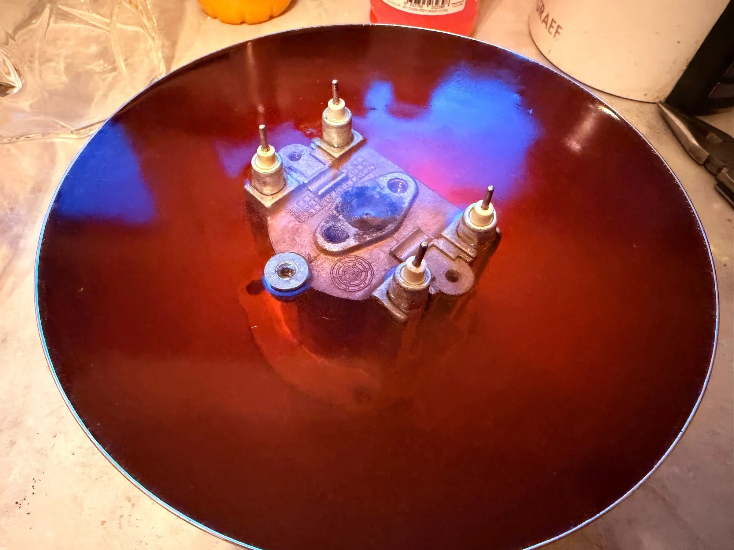 The aluminium boiler casting lying in a bowl of dark red descaler, its element terminals and thermostat studs sticking out of the liquid