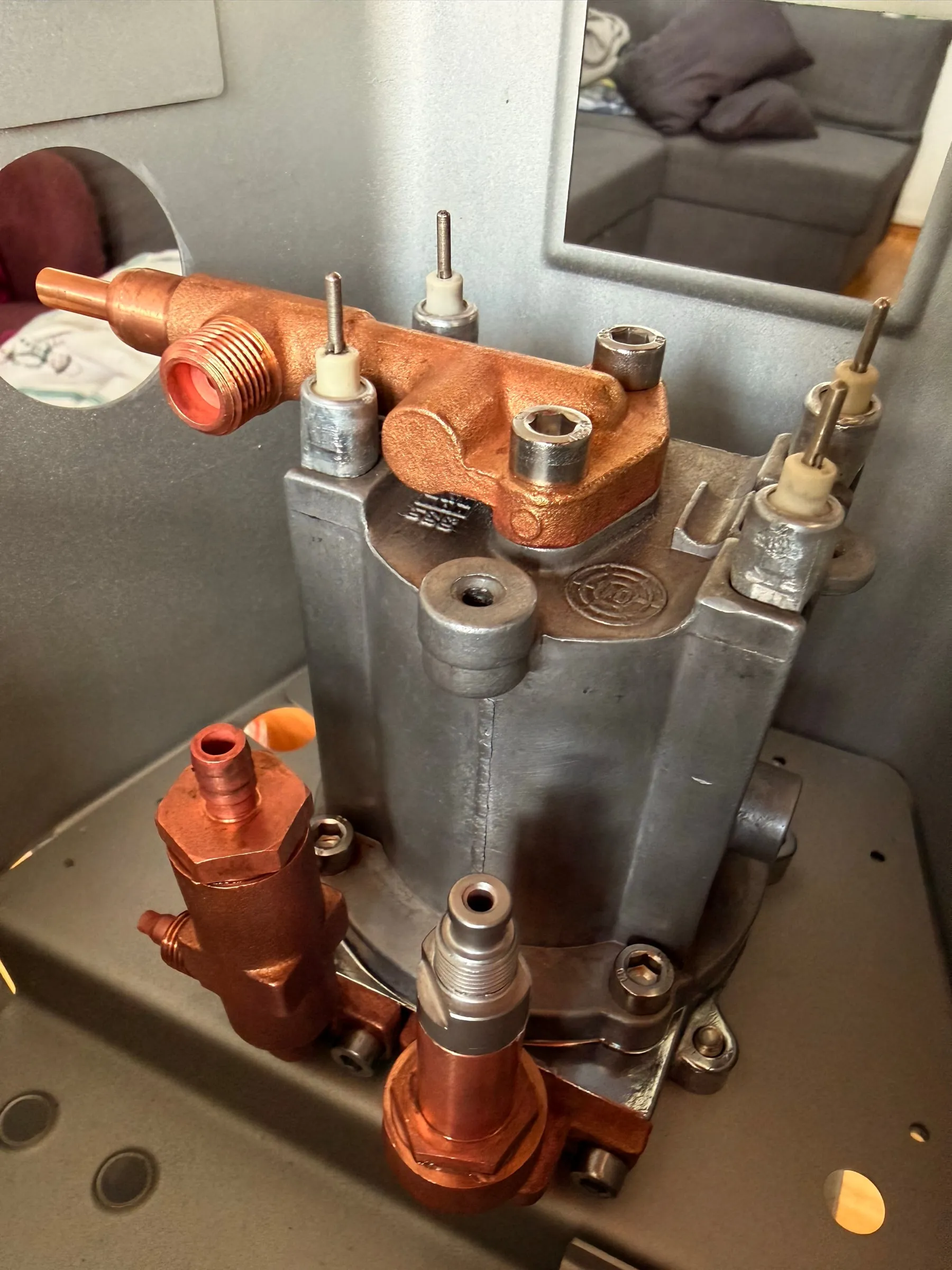 The reassembled boiler with its brass fittings sitting in the freshly painted aluminium-silver frame, the polished rim reflecting the room