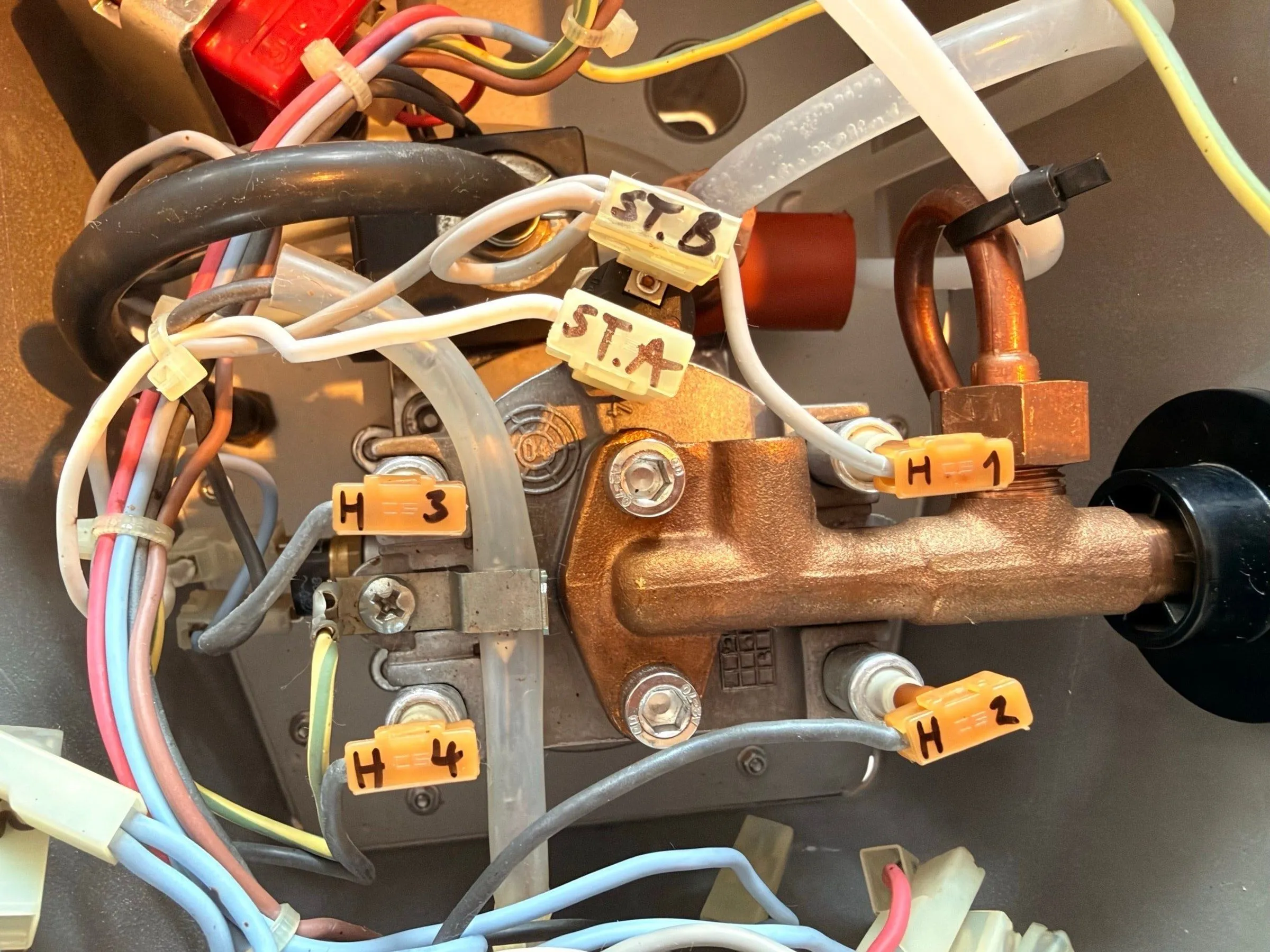 Looking down onto the boiler with the brass fittings and the two thermostats: hand-written tape flags read H1, H2, H3 and H4 on the heater wires and ST.A and ST.B on the wires to the steam thermostat