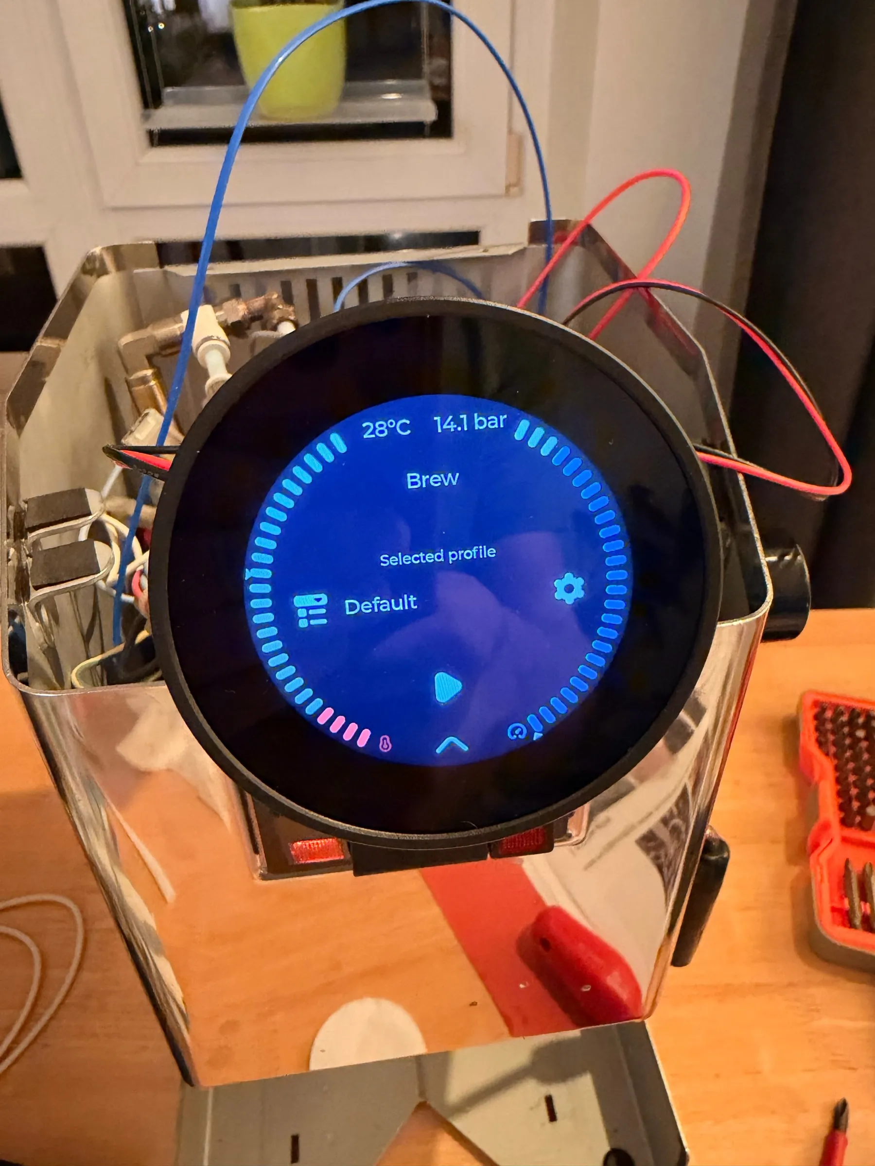 The same display a minute later showing the brew screen: 28 degrees and 14.1 bar in the header, the profile Default selected, a play button in the middle