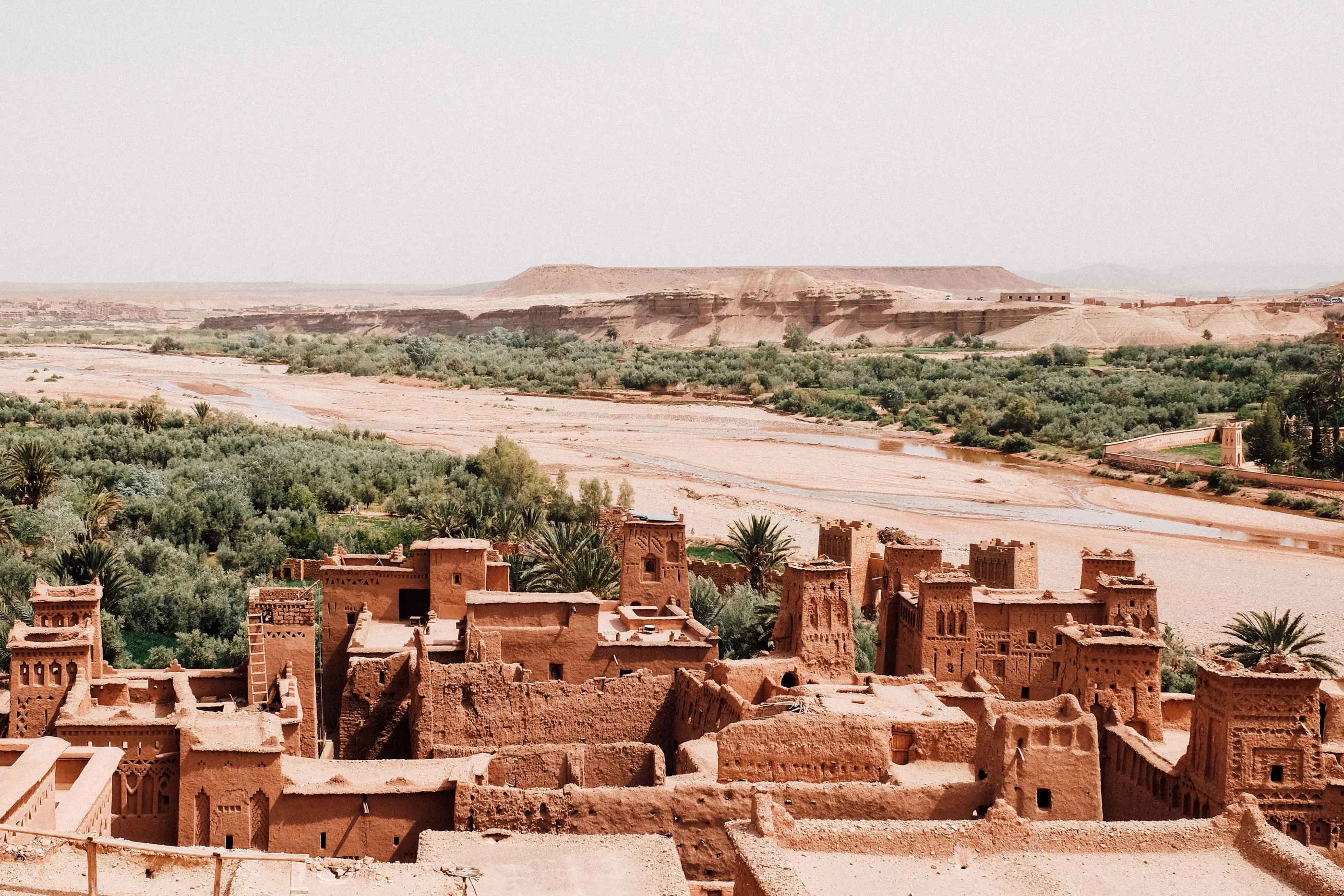 Kasbah of mud-brick houses above a green river oasis, desert hills behind