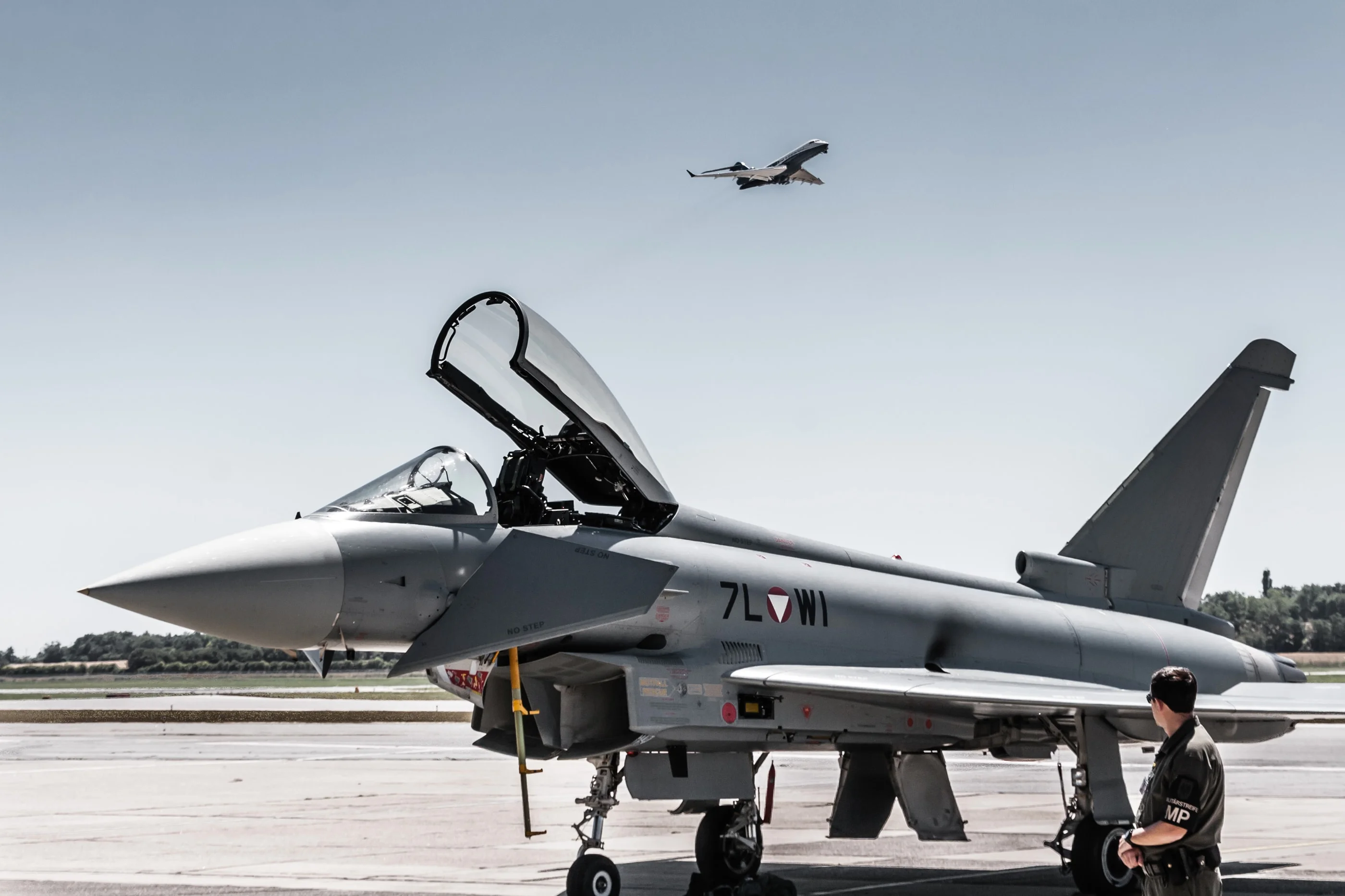 Eurofighter on the apron while a second jet flies overhead