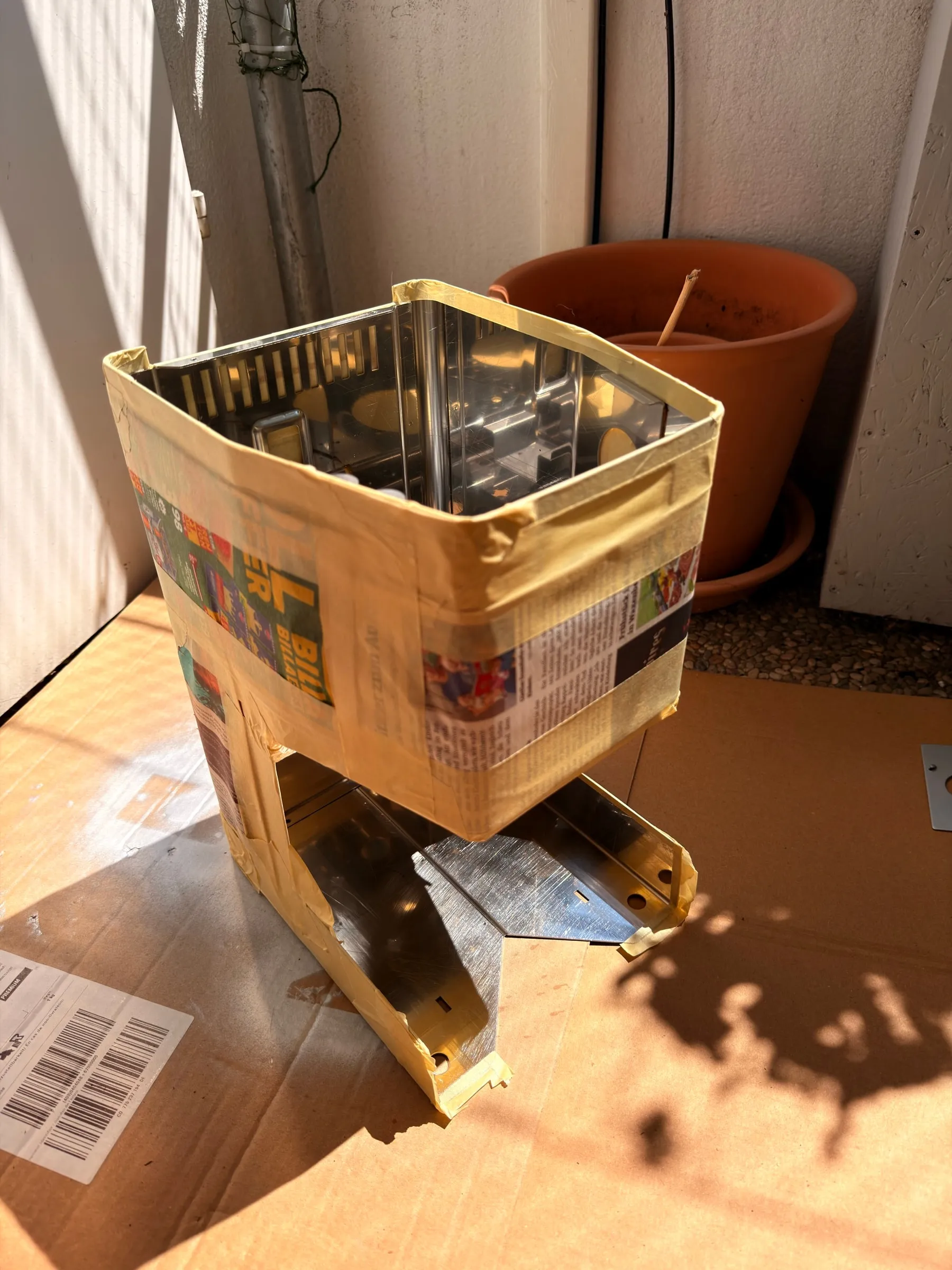 The housing on a sheet of cardboard on a sunny terrace, wrapped in crepe tape and newspaper so that only the inner steel surfaces are exposed
