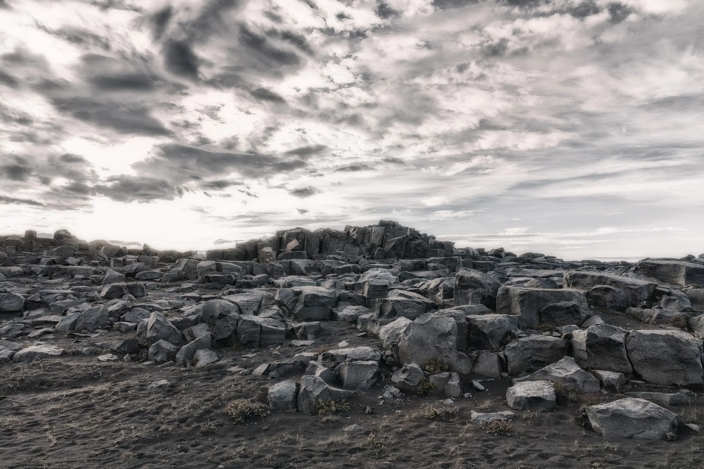 Black lava rocks under a cloudy sky, in black and white