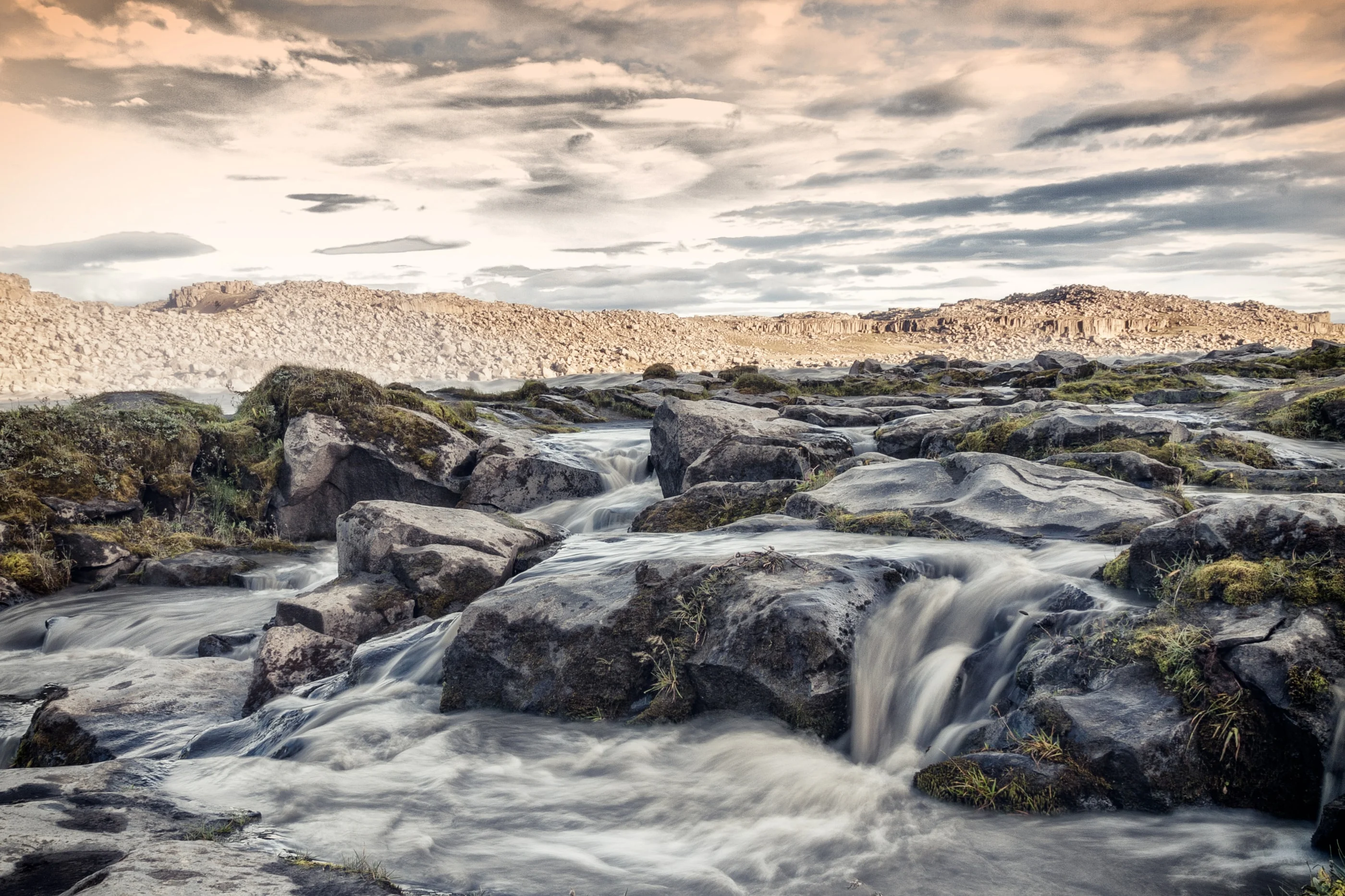 River cascading over dark rocks under evening clouds