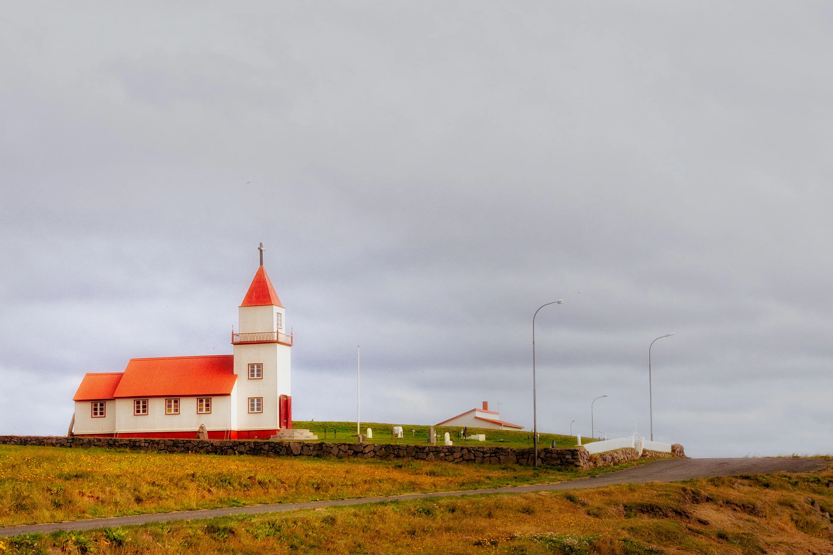 Small white church with a red roof and tower on a plain