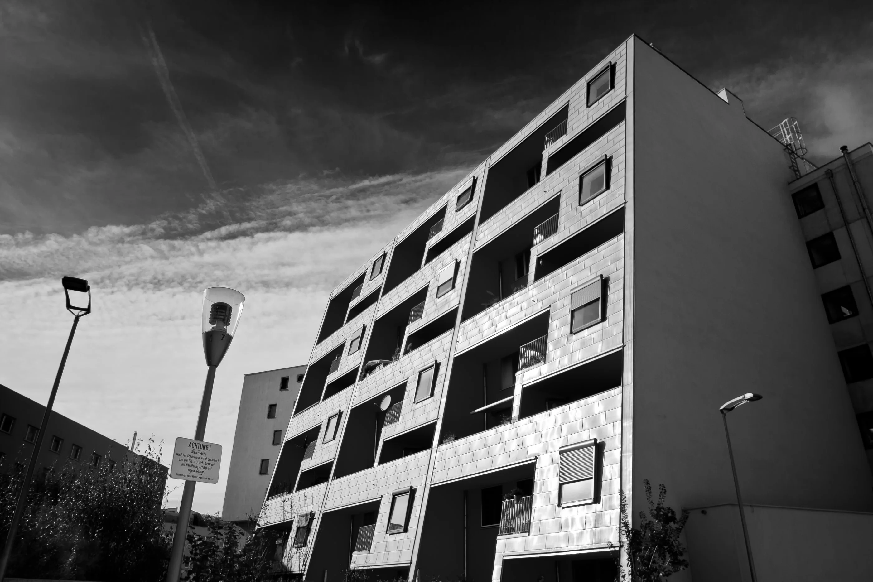 Kabelwerk apartment block with recessed balconies under a dark sky, in black and white