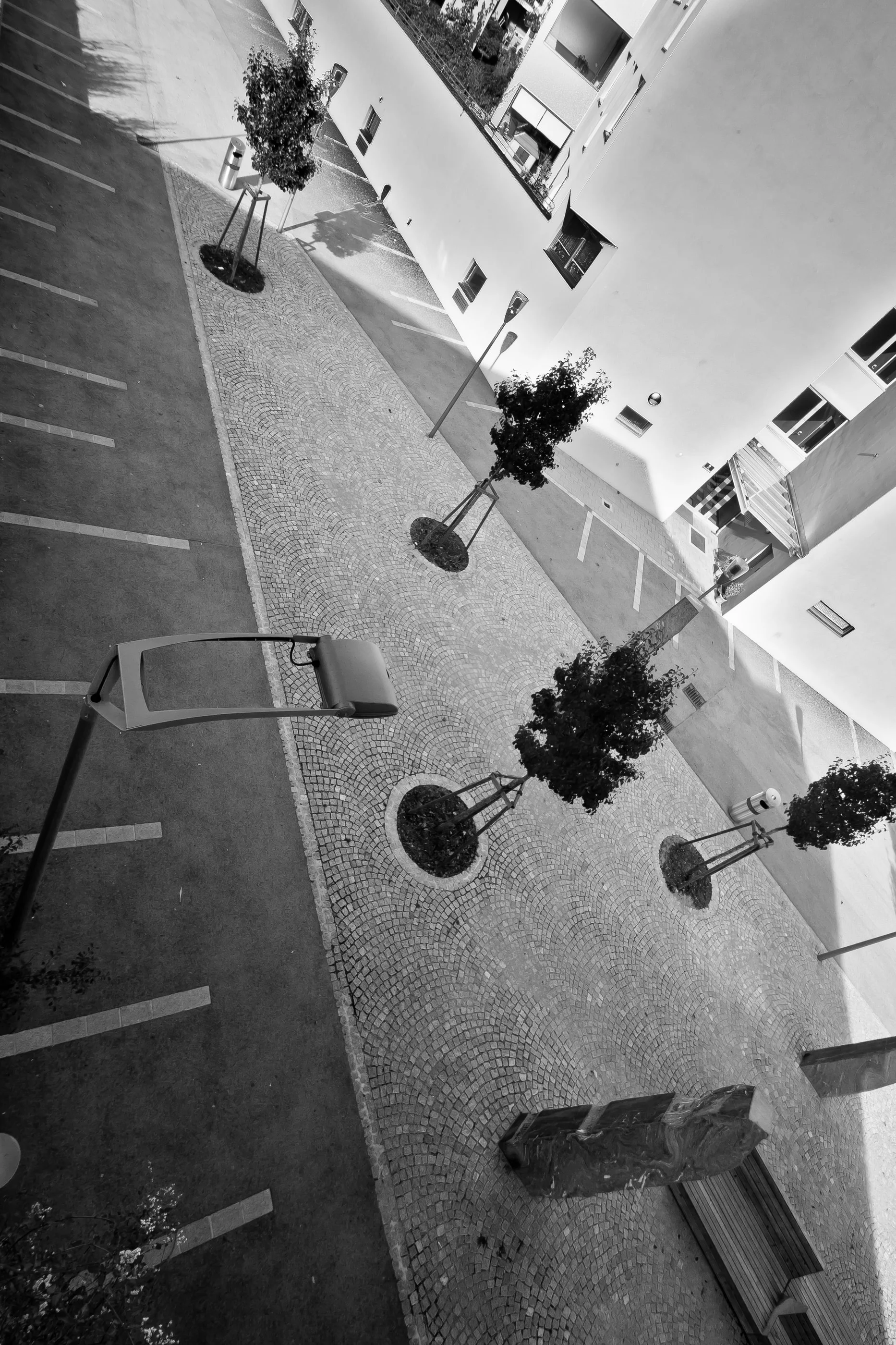 Plaza with tree planters seen steeply from above, between apartment blocks