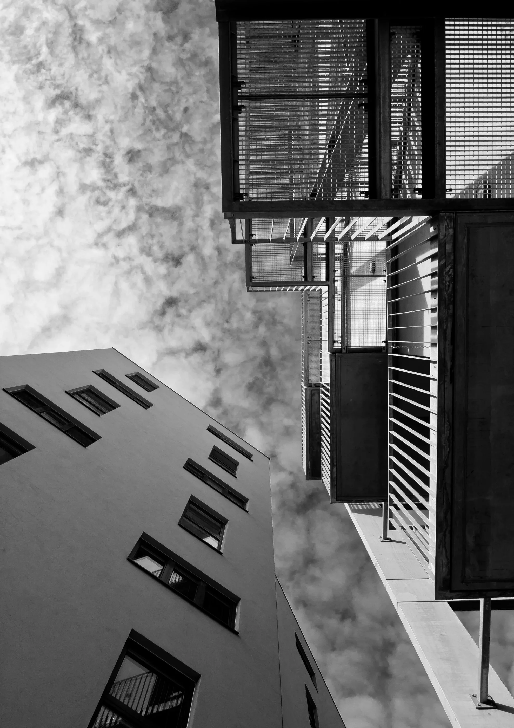 Balcony railings and a facade seen straight up against a cloudy sky