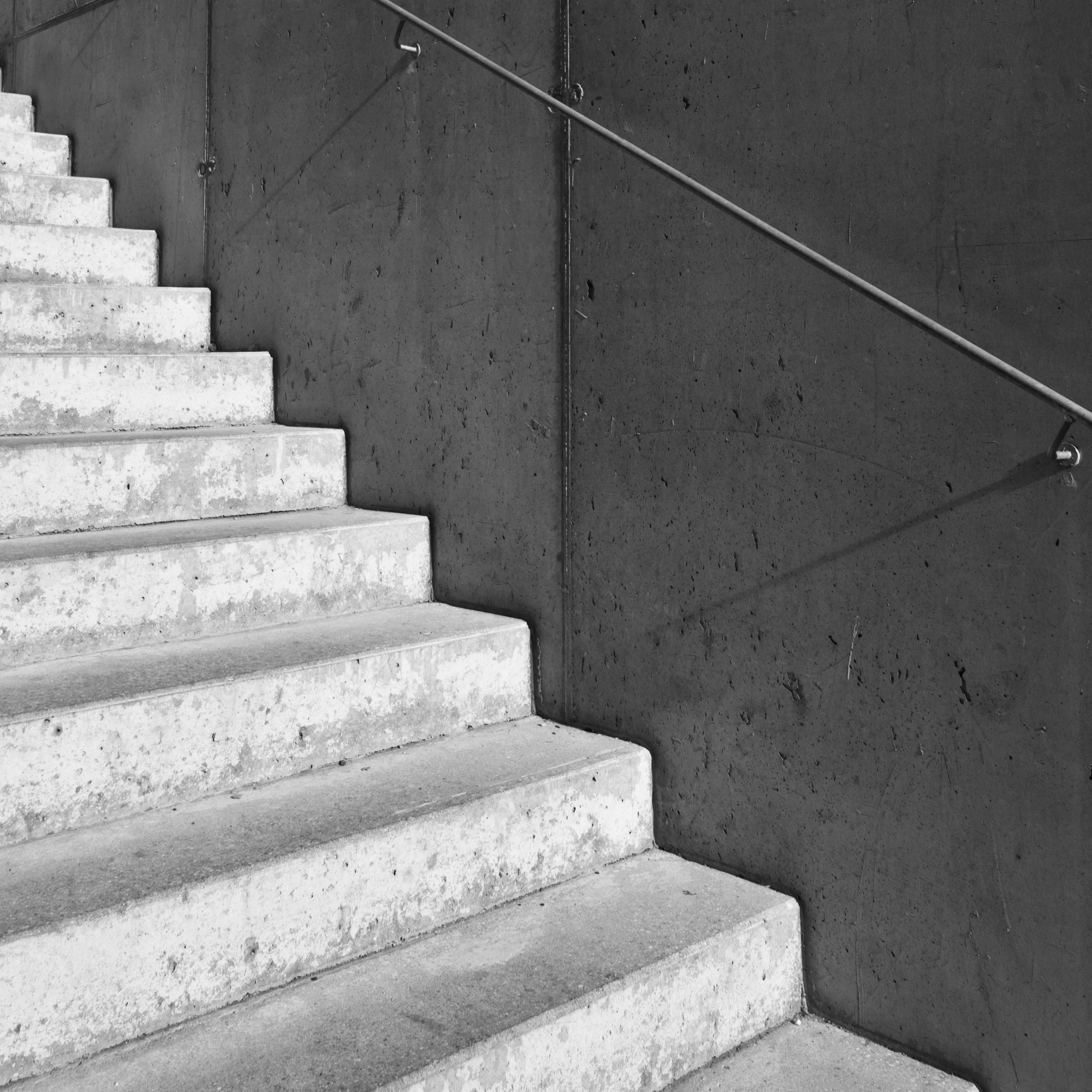 Concrete stairs with a handrail along a wall