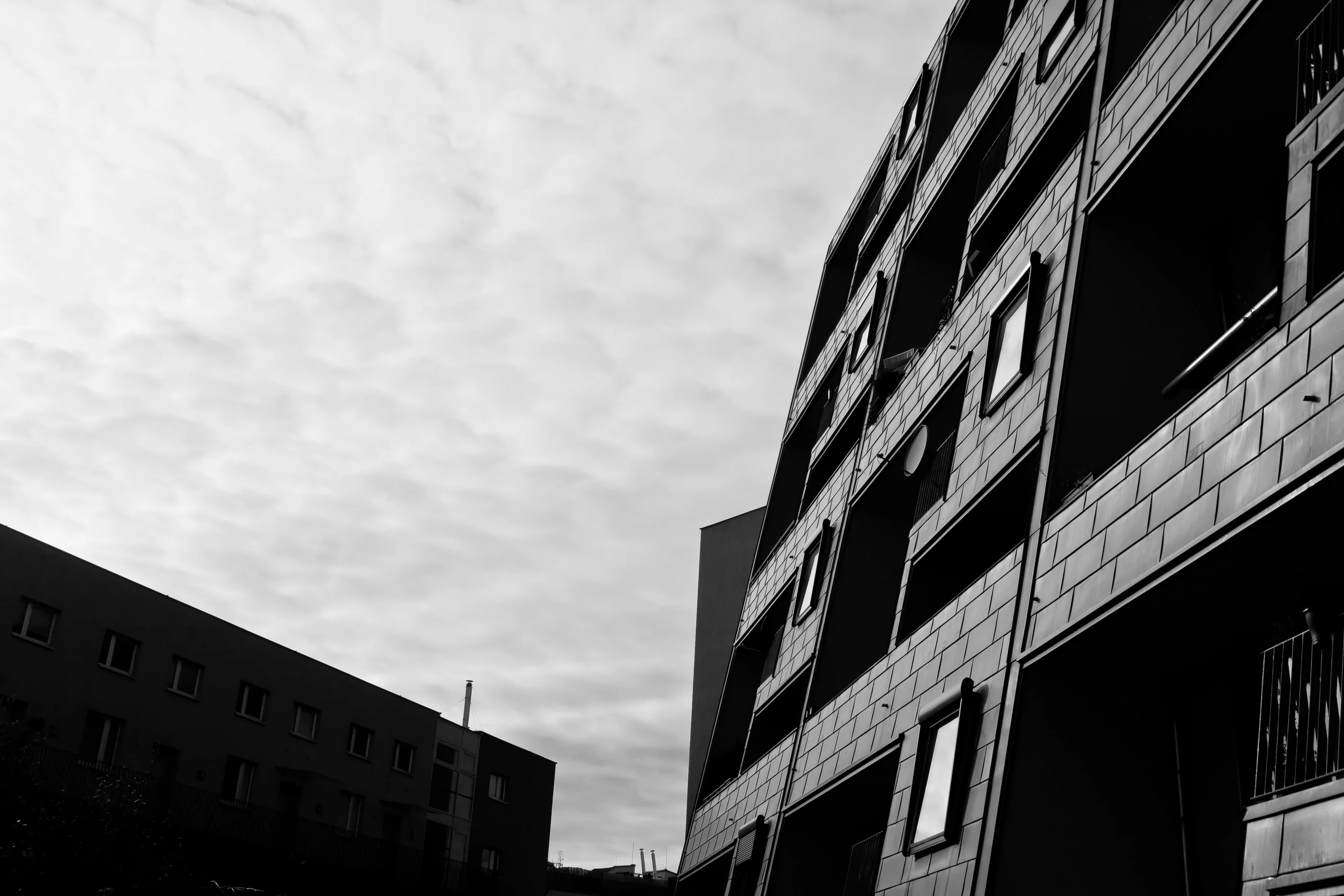 Apartment block with balconies rising diagonally against a cloudy sky