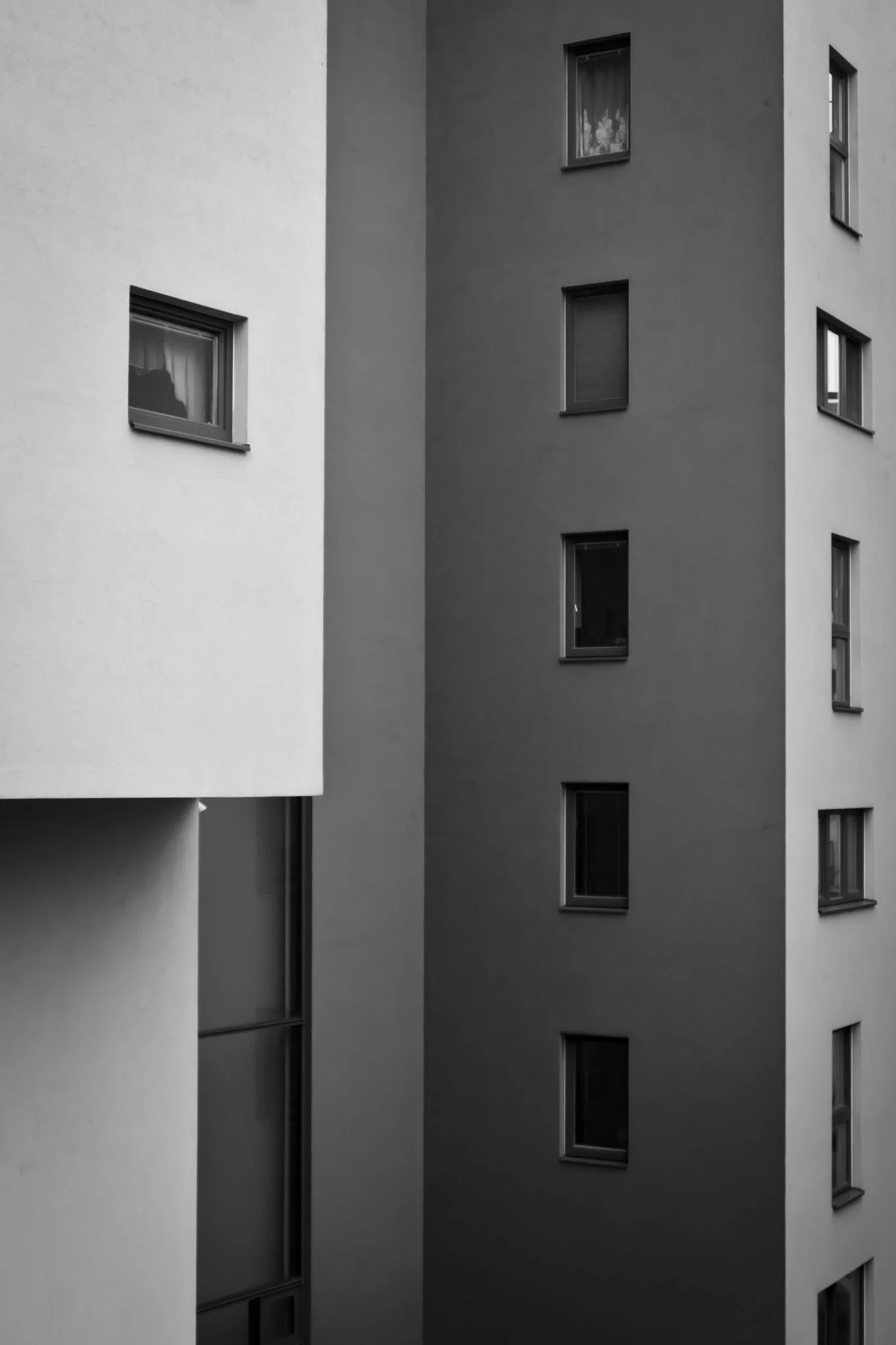 Narrow gap between a white and a dark apartment block with rows of windows