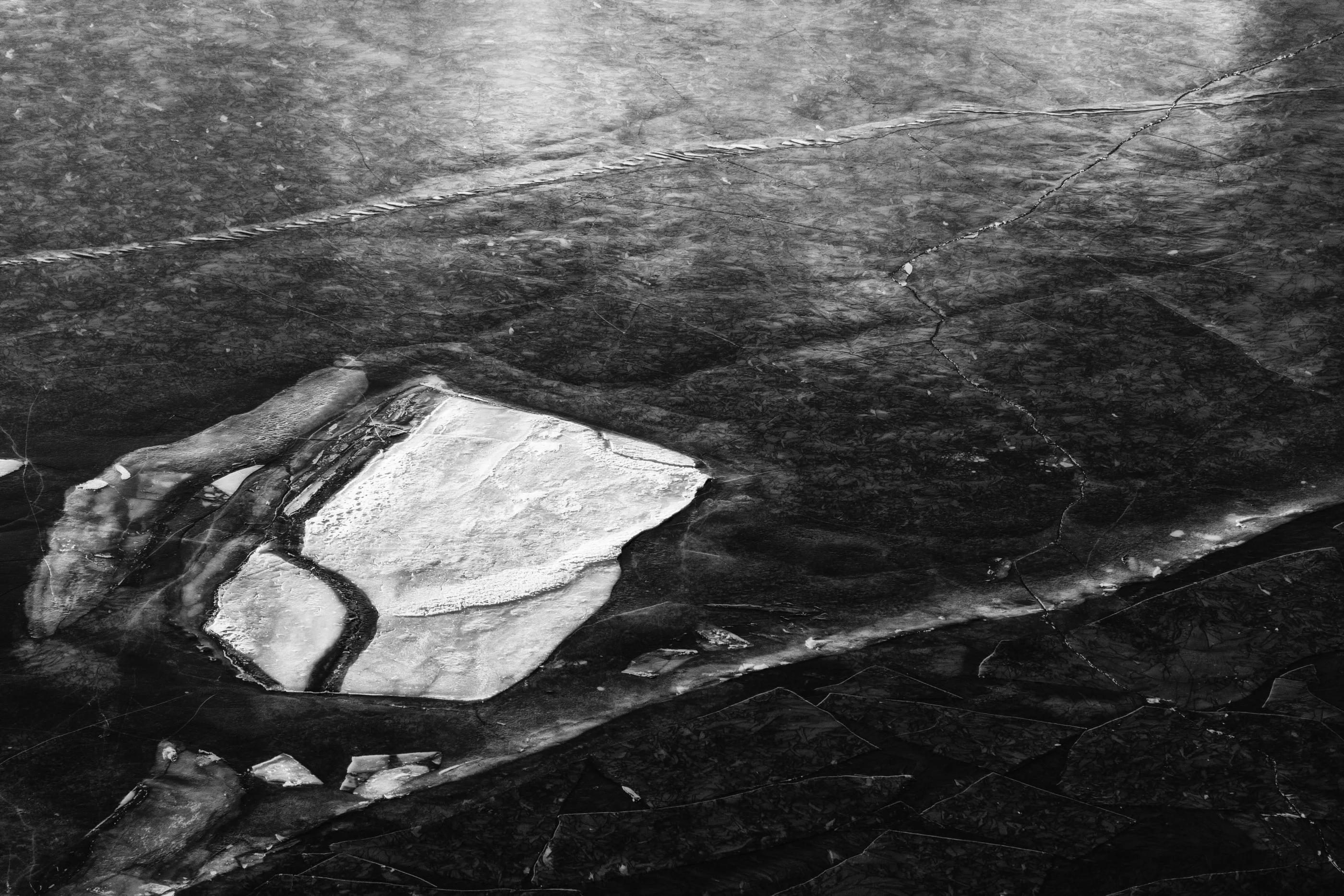 Pieces of broken ice on a dark frozen lake, in black and white