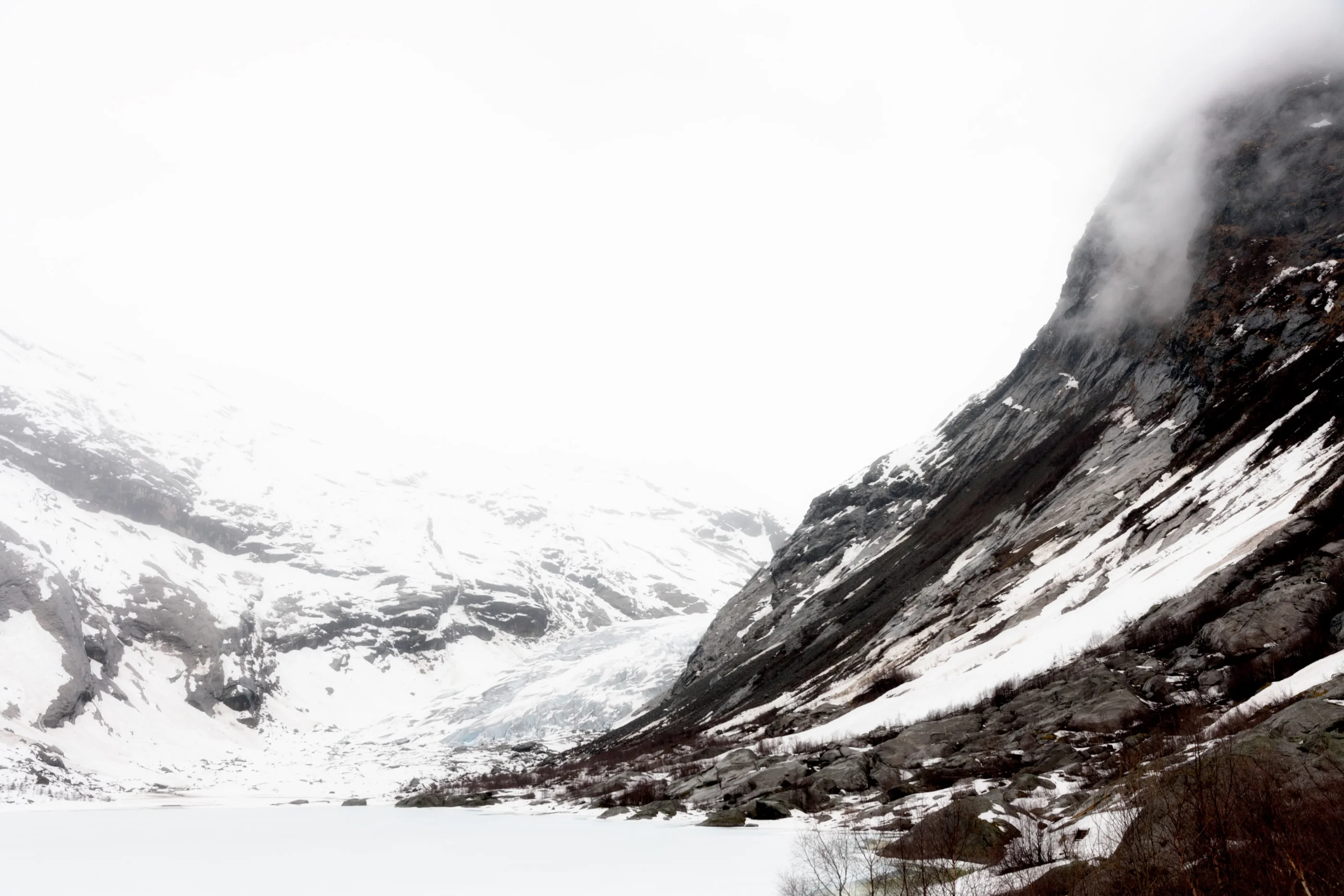 Snowy valley with fog rolling over dark mountain slopes
