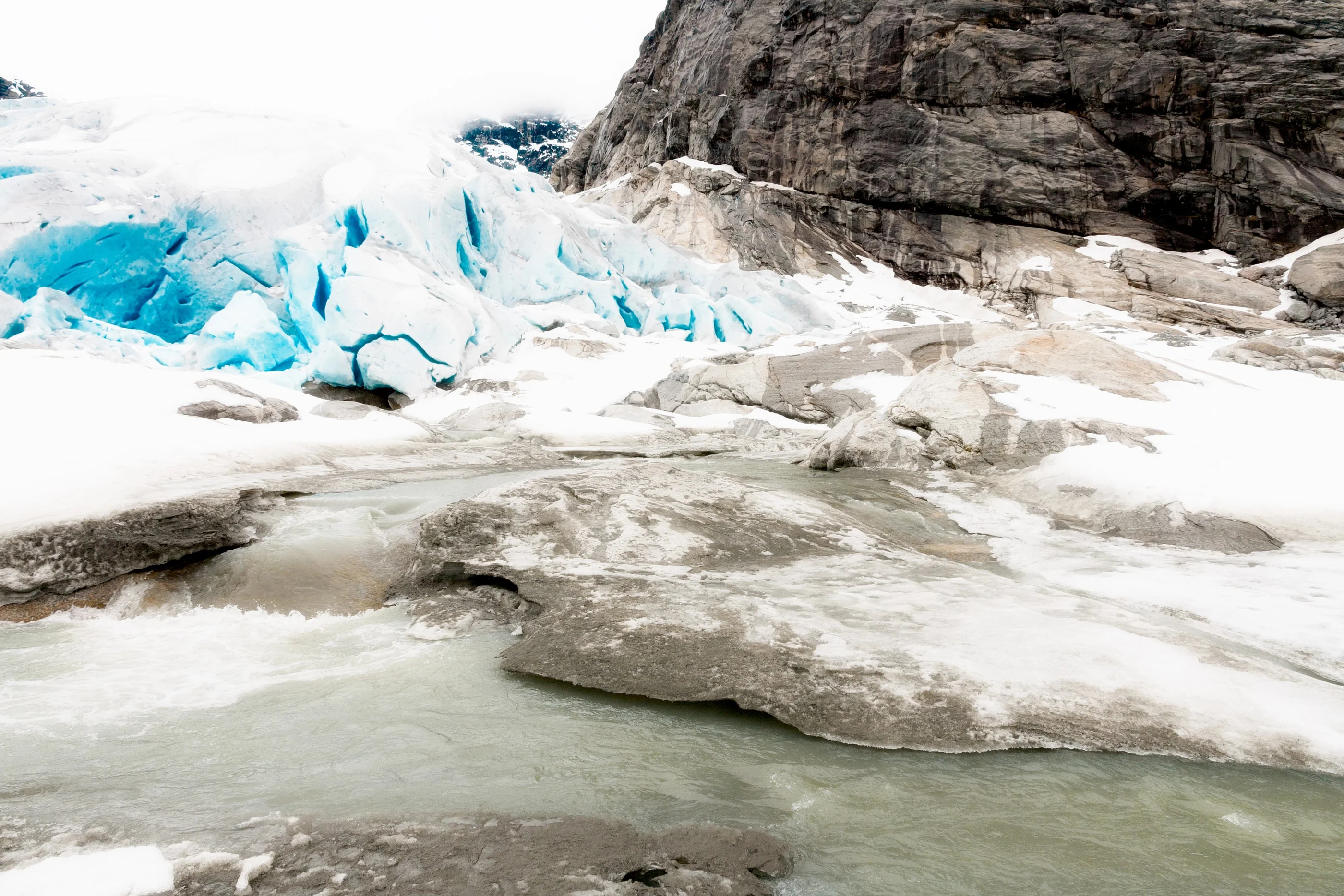Blue glacier ice above a meltwater pool and rounded rocks