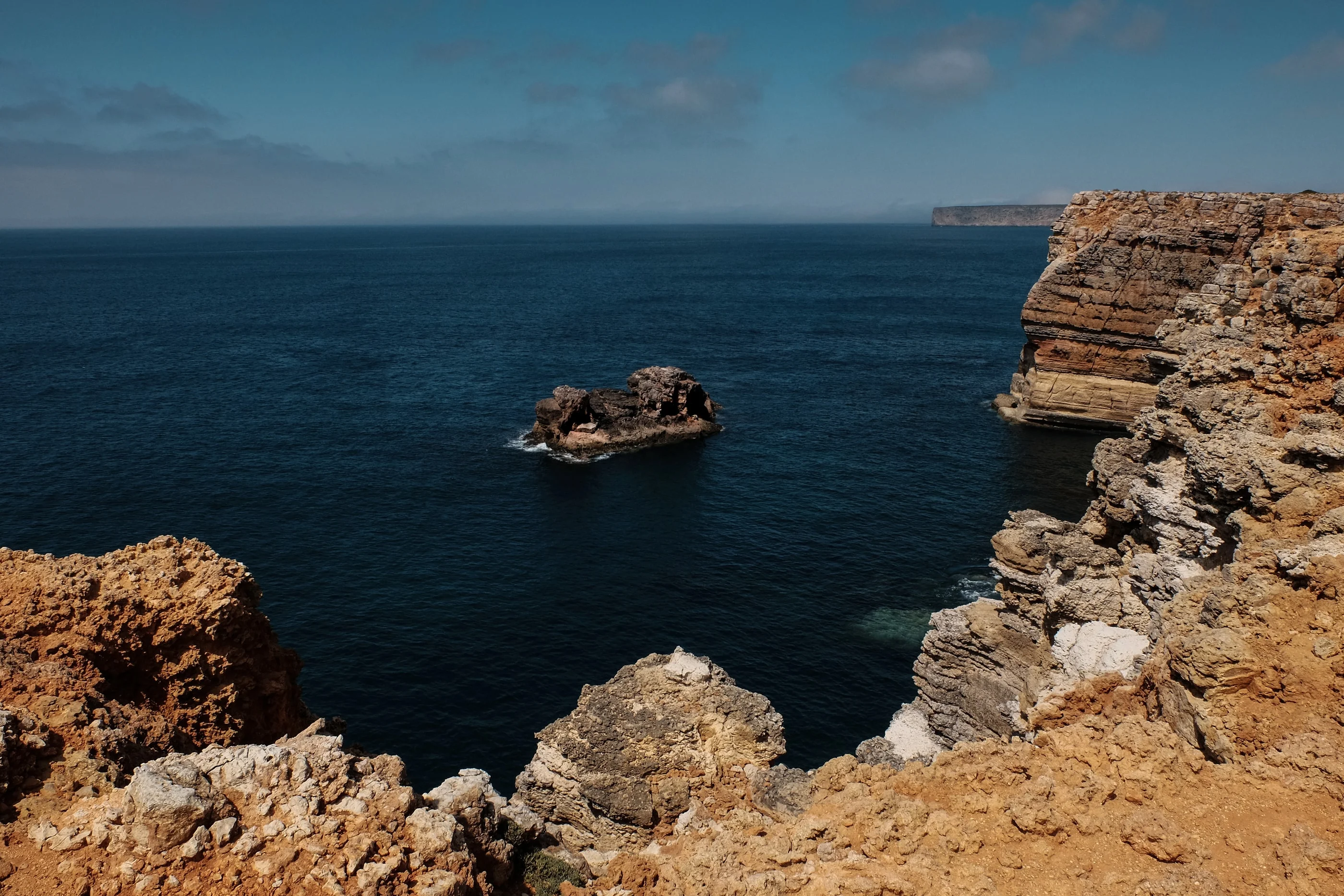 Sandstone cliffs and a rock island in a deep blue bay