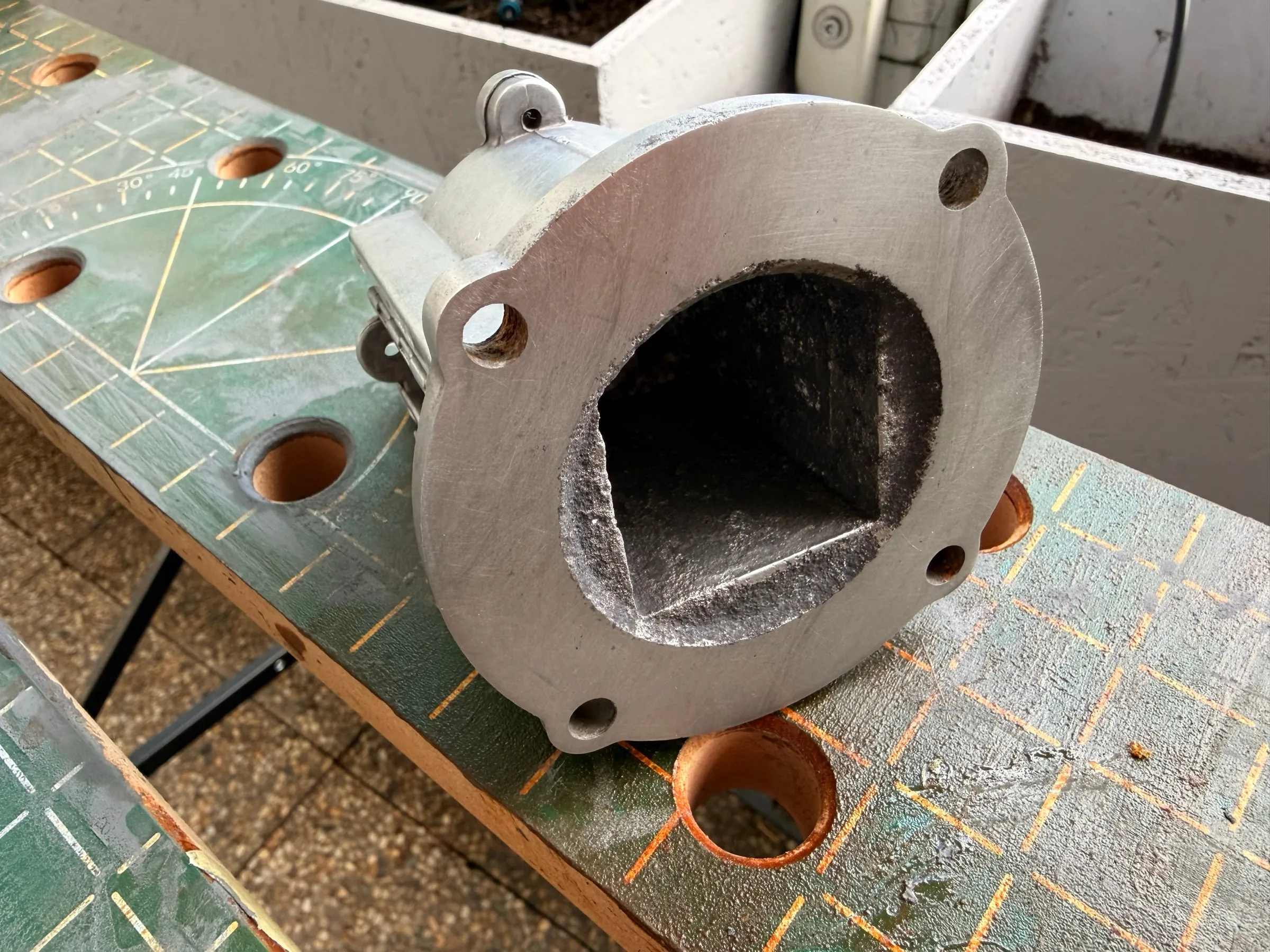 Close-up of the lapped boiler flange: the machined ring face bright and even, the inner bore still dark, four bolt holes around it