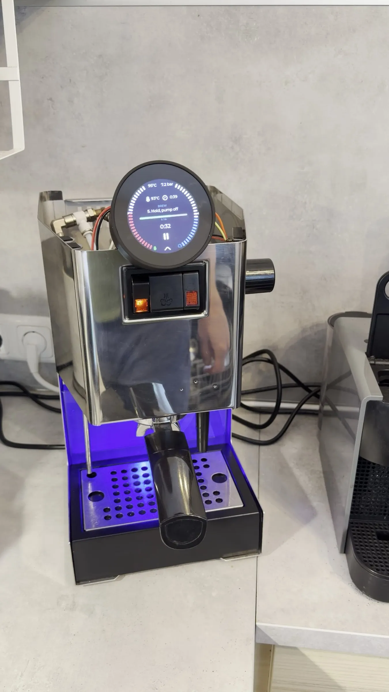 The machine on the worktop during phase 5 of the self-test, the display reading 7.2 bar with the pump off and the valve open, the drip tray lit blue