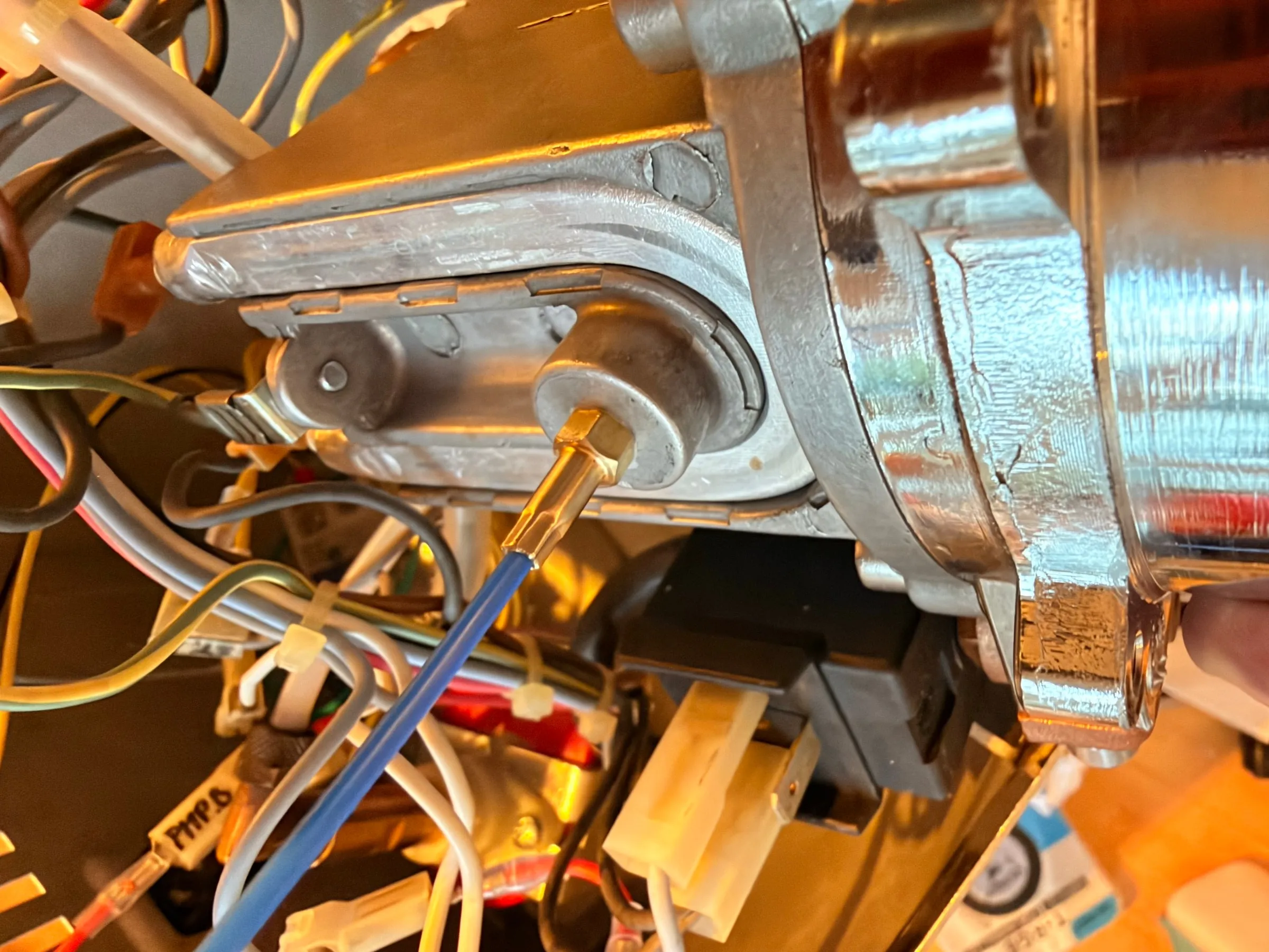 The boiler in the machine seen from the side: the probe with its blue cable screwed into the thread of the brew thermostat, the brass boiler fittings and the labelled wires around it