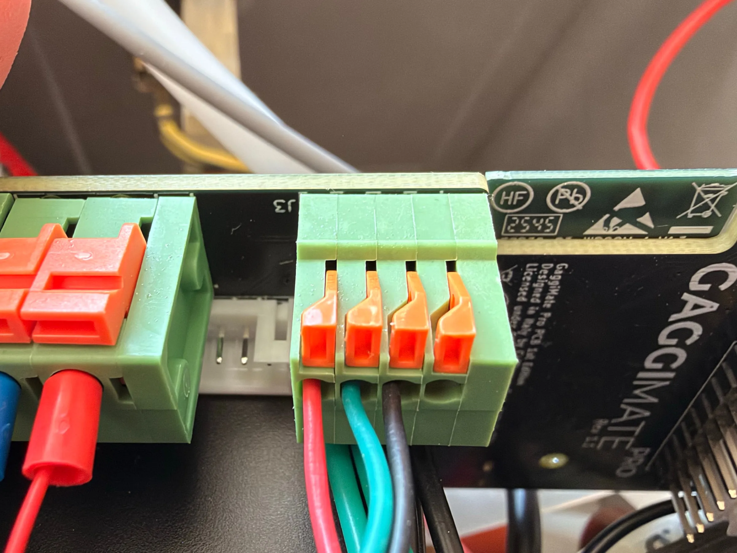 The green push-in terminal block on the board with the sensor's red, turquoise and black wires in the first three of its four positions and the fourth position empty, the orange levers open above them