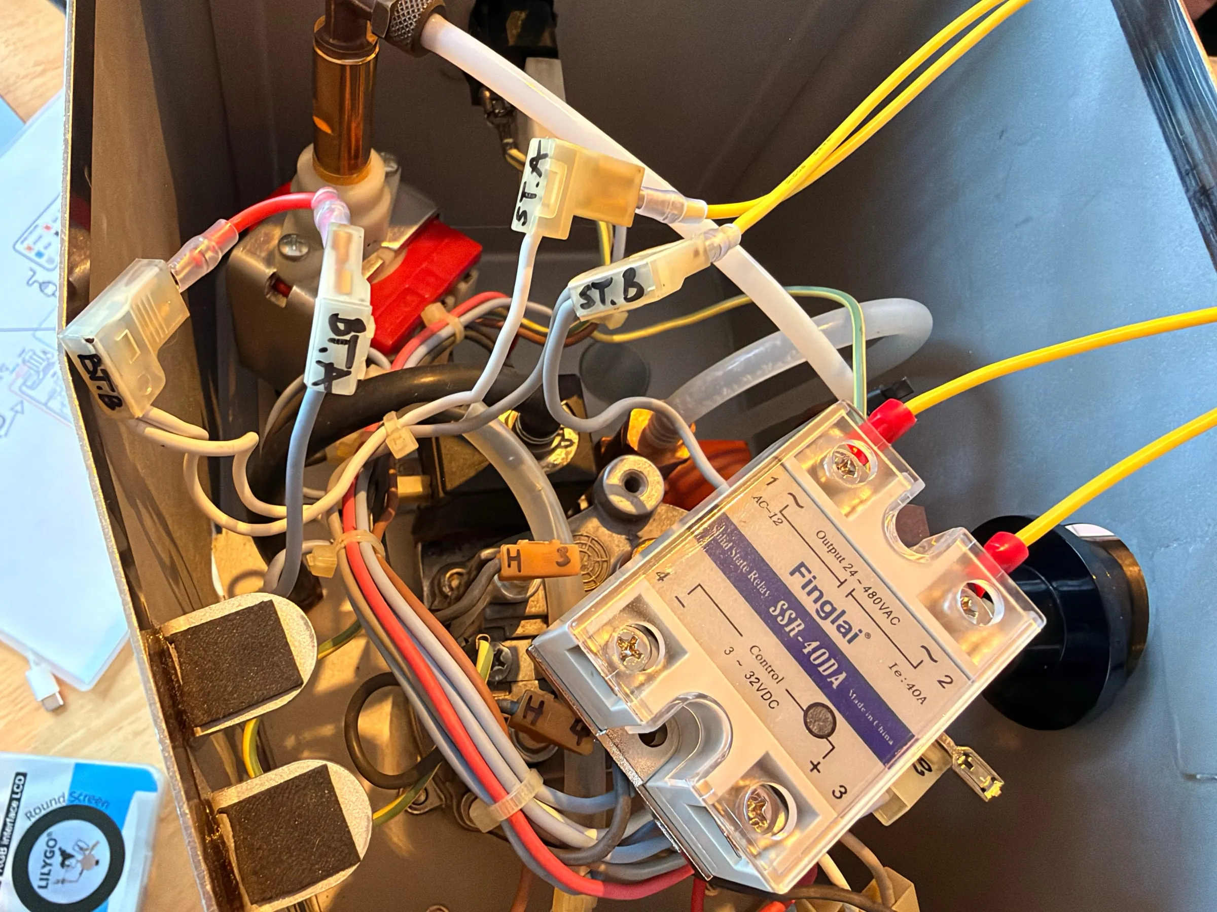 Looking into the housing: the white Finglai solid-state relay mounted on the frame with the two yellow mains wires from the thermostat position on its big terminals and two thin control wires on the small ones, labelled wires ST.A, ST.B and H3 around it, the copper steam pipe above