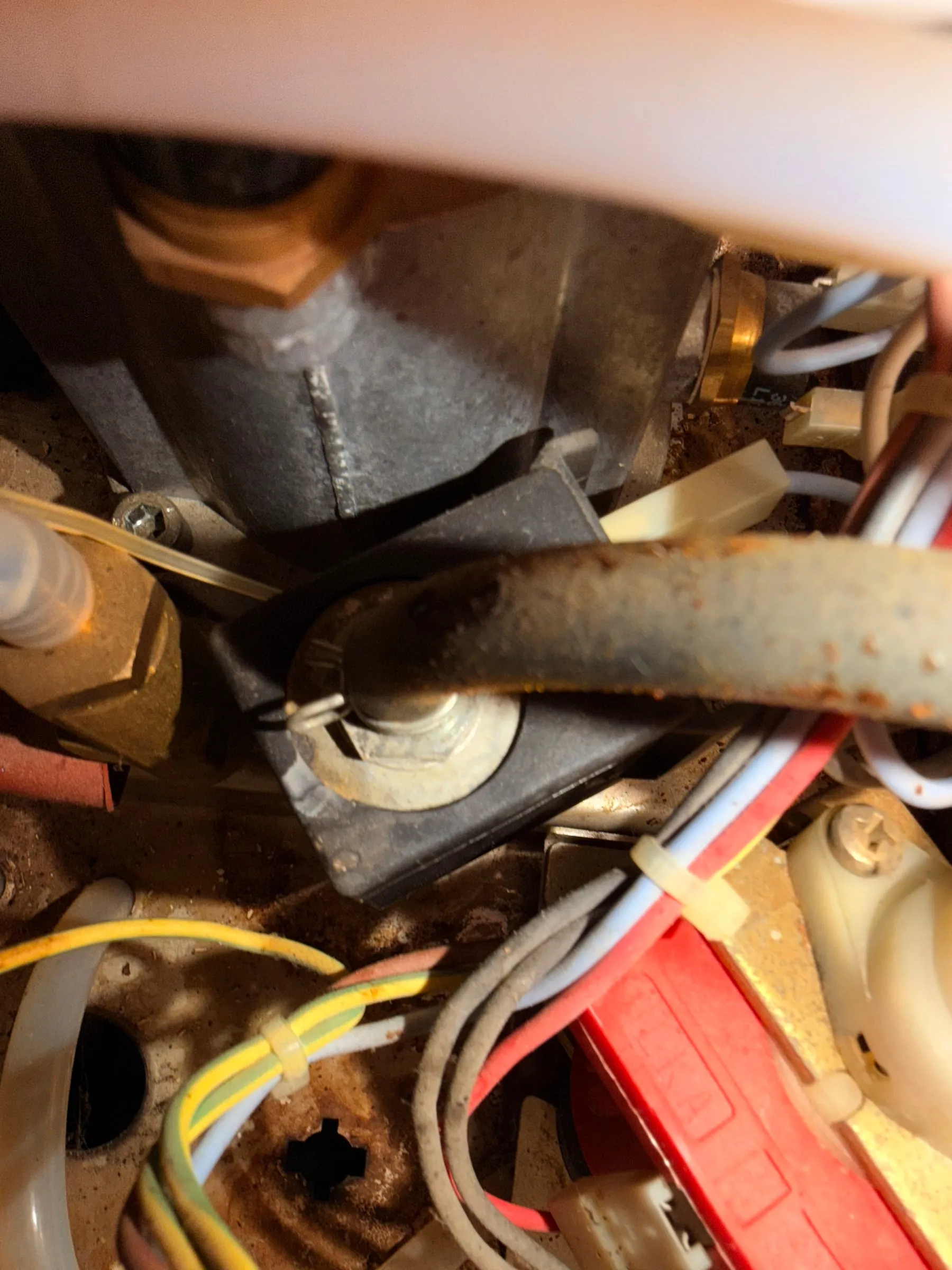 Close-up of the diagonal steel strut inside the base with distinct orange rust spots next to brass fittings and cable ties