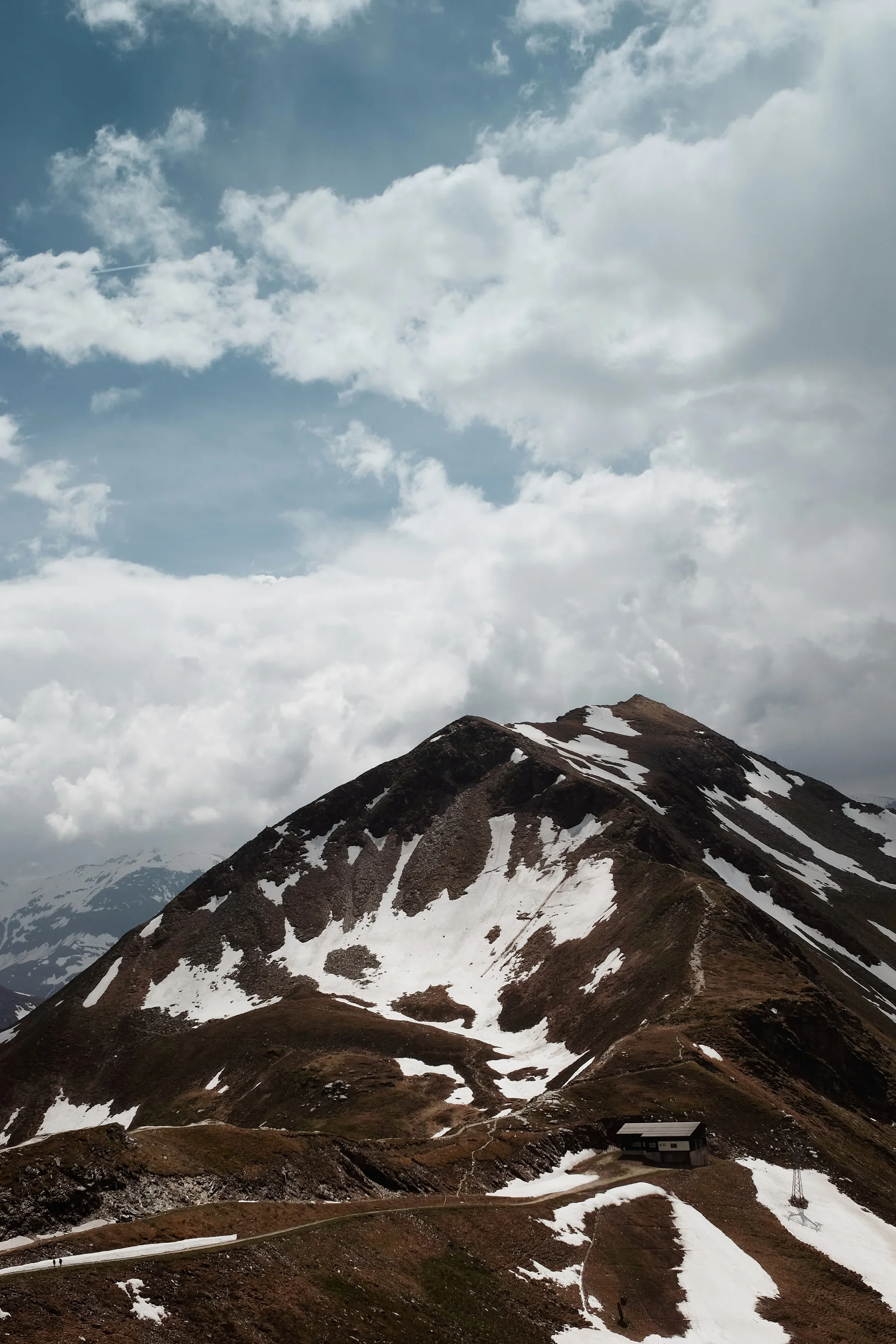 Snow-streaked peak under towering white clouds