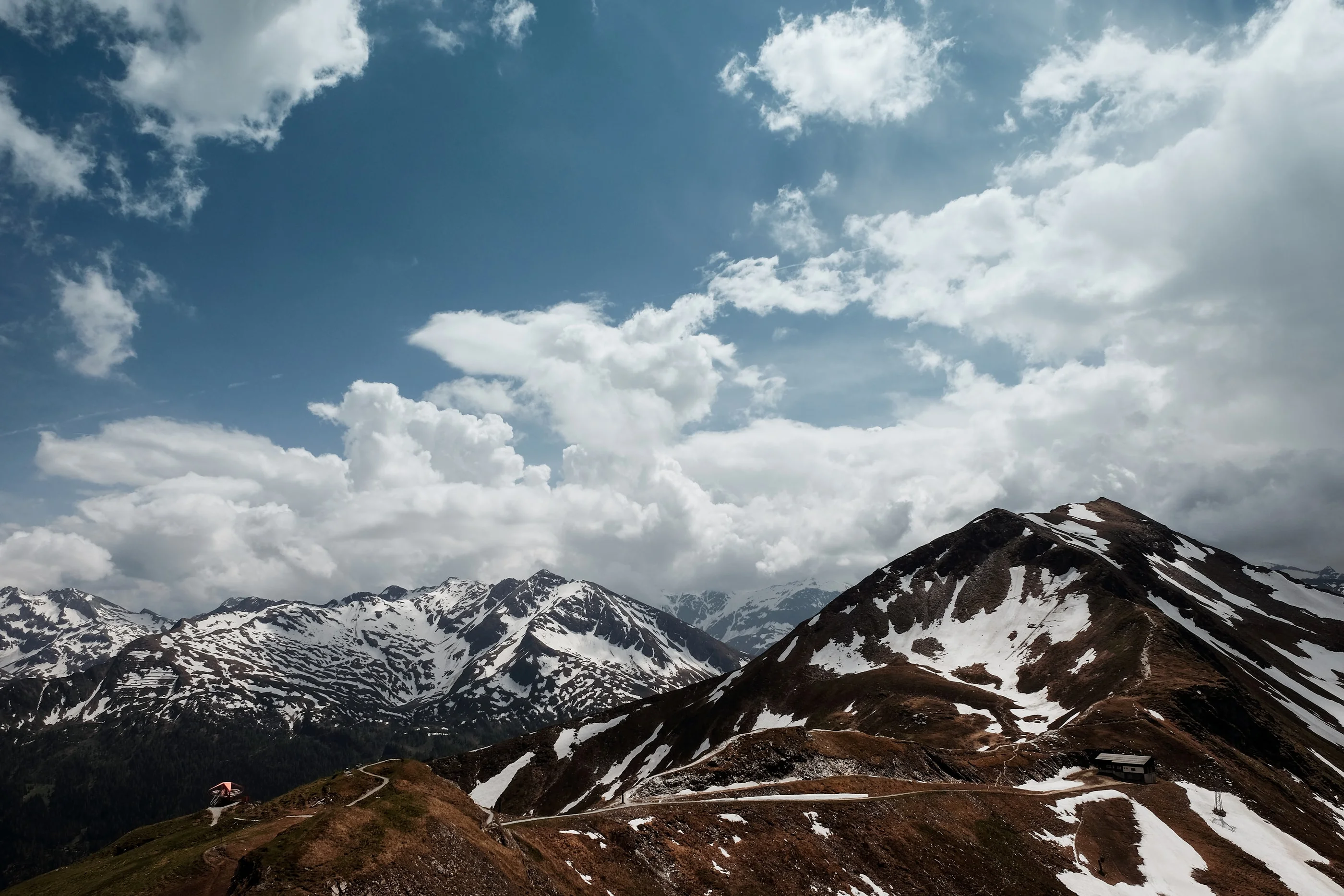 Mountain ridge with snow patches below billowing clouds