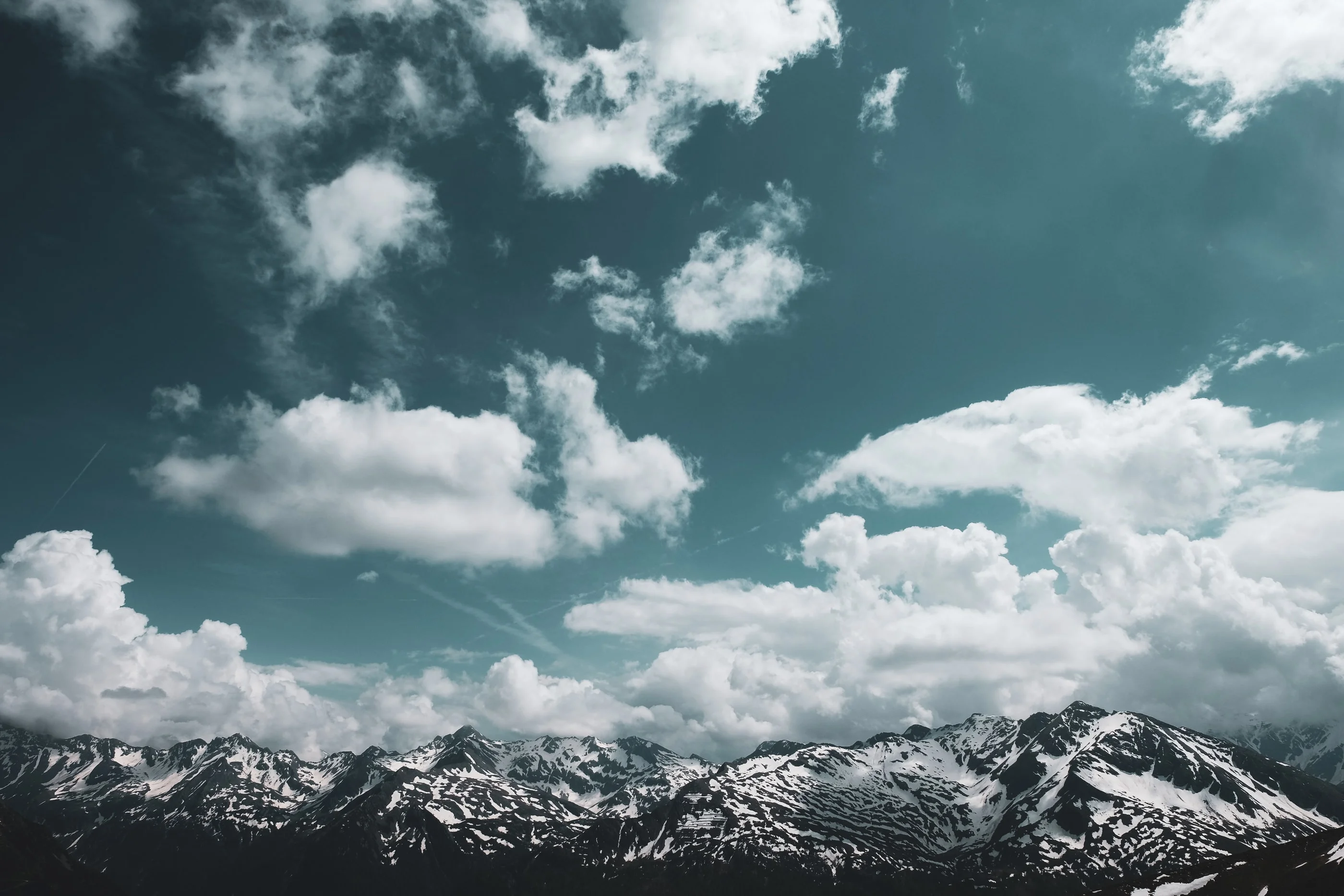 Distant snowy mountain range under scattered clouds
