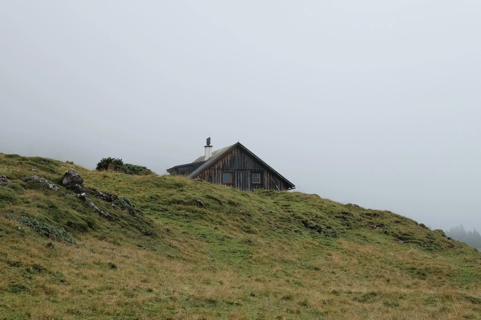 Wooden hut on a grassy ridge in fog