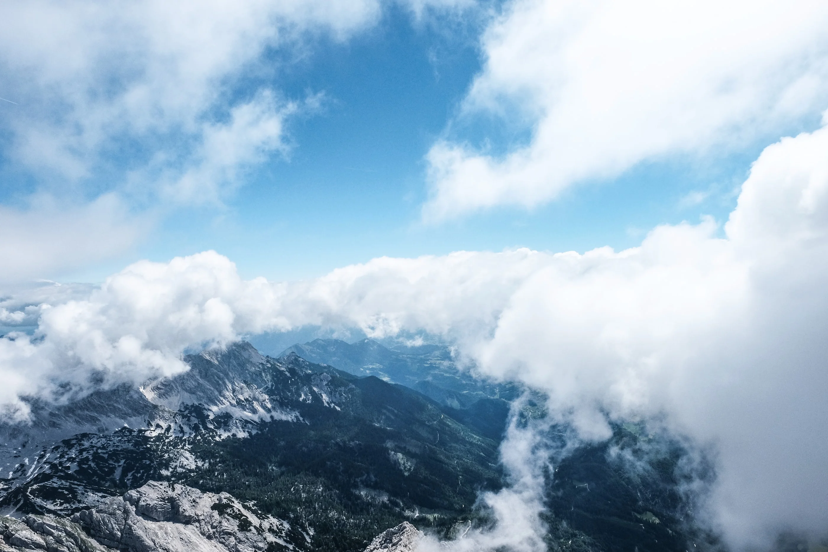 Clouds drifting over the mountains below the summit, blue sky above