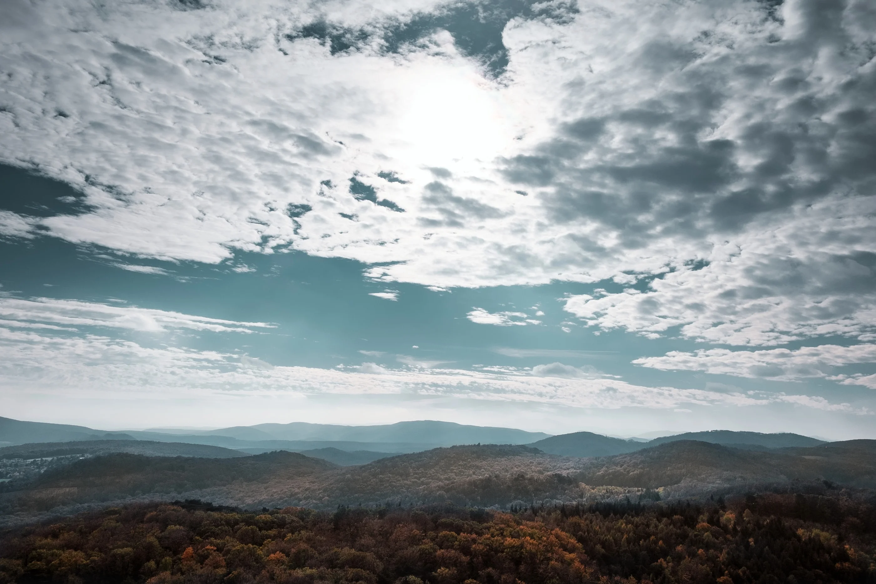 Sunlight breaking through clouds over forested hills